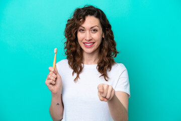 Wall Mural - Young caucasian woman brushing teeth isolated on blue background points finger at you with a confident expression