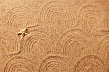 Wall Mural - A pattern in the form of waves on the sand on the beach and a starfish. Natural background.