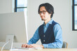 © HML - パソコンに向かってタイピングをする若い男性