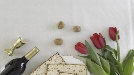 Wall Mural - Matzah shape of heart with red tulips, bottle of wine and walnut on white background. Traditional Holiday on Passover. Home symbol of lovely Jewish family in pesach. top view