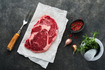 Wall Mural - Raw fresh ribeye steak or Rib-eye steak. Raw fresh marbled meat Ribeye Black Angus and seasonings pepper, rosemary, thyme and salt on old wooden rustic background. Top view and copy space.