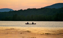 Silhouette Of Two People In A Canoe At Sunset