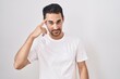 © Krakenimages.com - Handsome hispanic man standing over white background smiling pointing to head with one finger, great idea or thought, good memory