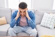 © Krakenimages.com - Young hispanic man stressed sitting on sofa at home