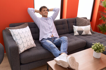 Canvas Print - Young hispanic man relaxed with hands on head sitting on sofa at home