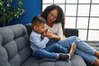 © Krakenimages.com - Mother and son drinking glass of water sitting on sofa at home