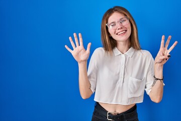 Canvas Print - Beautiful woman standing over blue background showing and pointing up with fingers number eight while smiling confident and happy.