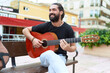 © Krakenimages.com - Young hispanic man musician playing classical guitar sitting on bench at park