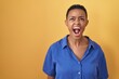 © Krakenimages.com - African american woman standing over yellow background angry and mad screaming frustrated and furious, shouting with anger. rage and aggressive concept.