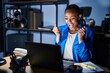 © Krakenimages.com - Beautiful african american woman working at the office at night celebrating surprised and amazed for success with arms raised and open eyes. winner concept.