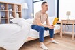 © Krakenimages.com - Young hispanic man sitting on bed with serious expression at bedroom