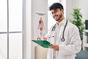 Canvas Print - Young hispanic man wearing doctor uniform writing medical report at clinic