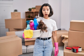 Canvas Print - Young hispanic woman cleaning at new home scared and amazed with open mouth for surprise, disbelief face