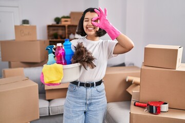 Sticker - Young hispanic woman cleaning at new home smiling happy doing ok sign with hand on eye looking through fingers