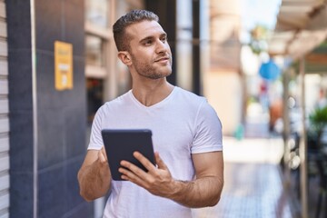 Wall Mural - Young caucasian man using touchpad with relaxed expression at street