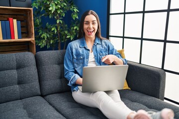 Wall Mural - Hispanic woman using laptop at home smiling happy pointing with hand and finger