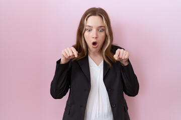 Sticker - Young caucasian business woman wearing black jacket pointing down with fingers showing advertisement, surprised face and open mouth