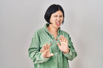 Sticker - Young asian woman standing over white background disgusted expression, displeased and fearful doing disgust face because aversion reaction.