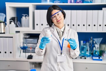 Wall Mural - Young asian woman working at scientist laboratory relaxed with serious expression on face. simple and natural looking at the camera.