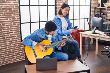 Sticker - Man and woman musicians playing classical guitar using smartphone at music studio