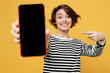 © ViDi Studio - Young fun woman wear casual striped black and white shirt hold in hand use point finger on mobile cell phone with blank screen workspace area isolated on plain yellow color background studio portrait.
