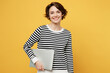 © ViDi Studio - Young smiling fun student IT woman wearing casual striped black and white shirt hold closed laptop pc computer look aside isolated on plain yellow color background studio portrait. Lifestyle concept.