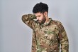 © Krakenimages.com - Arab man wearing camouflage army uniform suffering of neck ache injury, touching neck with hand, muscular pain