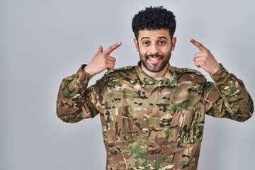 Sticker - Arab man wearing camouflage army uniform smiling pointing to head with both hands finger, great idea or thought, good memory