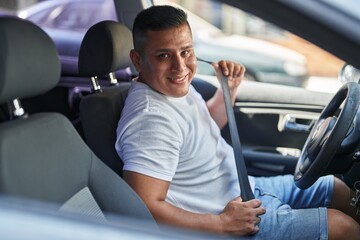 Wall Mural - Young latin man smiling confident wearing car belt at street