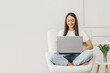 © Evgenia - Caucasian freelancer girl sits in a chair uses a laptop and looks at the monitor screen