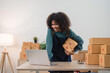 © Natee Meepian - Young attractive woman owner startup business work happy with box at home prepare parcel delivery in sme supply chain, online delivery idea concept