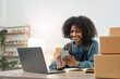 © Natee Meepian - Entrepreneur, small business, SME, freelance woman working from home with lots of boxes on the side. Use smartphones and laptops for commercial monitoring. online marketing packaging box online sale