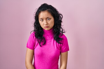 Poster - Young asian woman standing over pink background depressed and worry for distress, crying angry and afraid. sad expression.