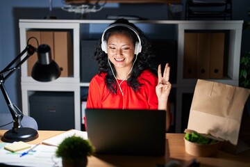 Wall Mural - Young asian woman working at the office with laptop at night showing and pointing up with fingers number three while smiling confident and happy.