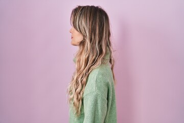 Poster - Young caucasian woman standing over pink background looking to side, relax profile pose with natural face with confident smile.