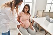 © Krakenimages.com - Young latin woman pregnant and doctor auscultating belly at clinic
