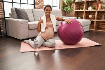 Sticker - Young pregnant woman sitting on yoga mat with pilates ball smiling happy and positive, thumb up doing excellent and approval sign