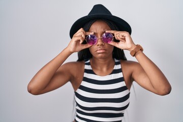 Canvas Print - Young african american with braids wearing hat and sunglasses trying to open eyes with fingers, sleepy and tired for morning fatigue