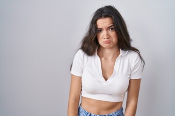 Sticker - Young teenager girl standing over white background depressed and worry for distress, crying angry and afraid. sad expression.