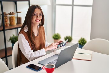 Sticker - Young beautiful hispanic woman using laptop counting dollars at home