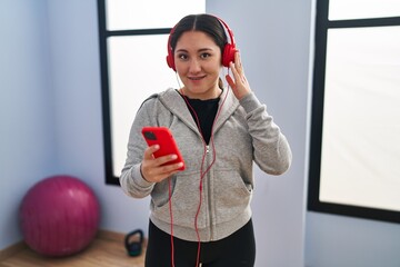 Wall Mural - Young hispanic woman smiling confident listening to music training at sport center