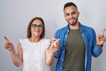 Canvas Print - Hispanic mother and son standing together smiling confident pointing with fingers to different directions. copy space for advertisement