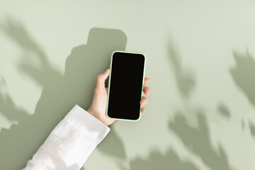 woman hold phone with black blank screen, minimal flat lay on olive green background. smartphone moc