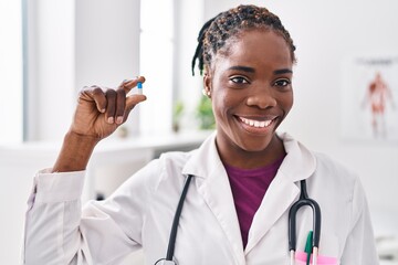 Poster - African american woman wearing doctor uniform holding pill at clinic