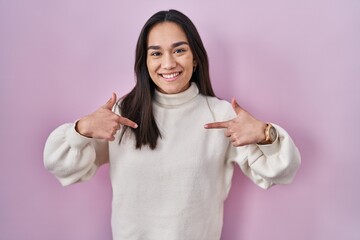 Poster - Young south asian woman standing over pink background looking confident with smile on face, pointing oneself with fingers proud and happy.