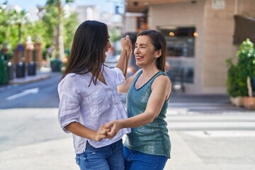 Wall Mural - Two women mother and daughter smiling confident dancing at street