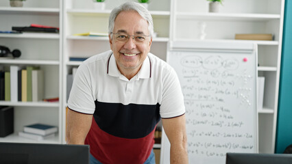 Canvas Print - Middle age man with grey hair teaching standing by white board at university classroom