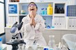 © Krakenimages.com - Hispanic girl with down syndrome working at scientist laboratory begging and praying with hands together with hope expression on face very emotional and worried. begging.