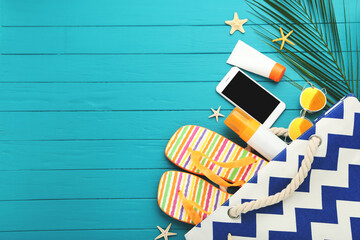 Wall Mural - Pair of flip flops with smartphone, starfishes, sunglasses and palm leaf on blue background