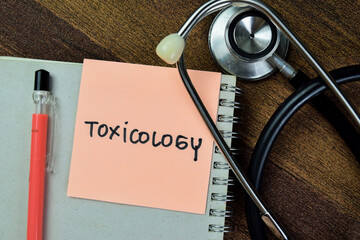 Wall Mural - Concept of Toxicology write on sticky notes with stethoscope isolated on Wooden Table.